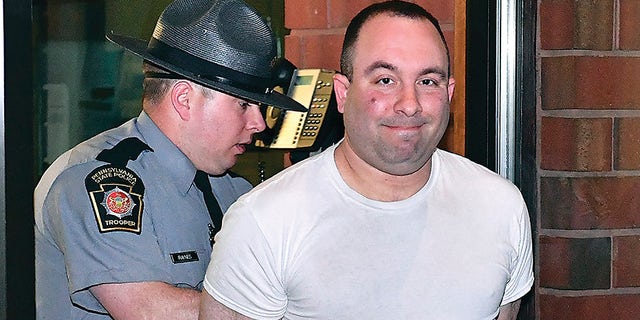 In this April 20, 2018, file photo, Bloomsburg Mayor Eric Bower, right, is escorted out of the State Police barracks in Bloomsburg, Pa., by Trooper Jason Raynes after being video arraigned by District Judge Doug Brewer on misdemeanor charges including criminal solicitation and patronizing prostitutes.