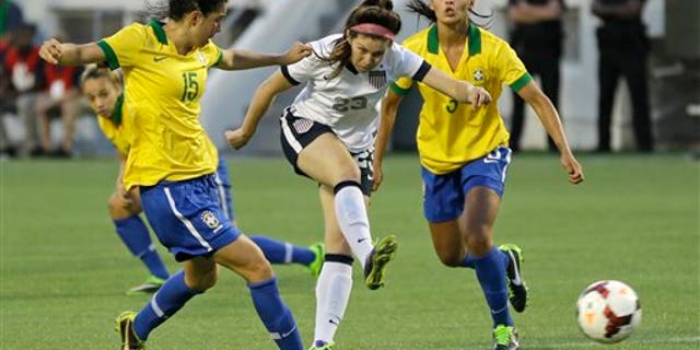 U.S. midfielder Erika Tymrak, center, scores a goal between Brazil midfielder Bia (15) and defender Calandrini (3) during the second half of an international friendly soccer match in Orlando, Fla., Sunday, Nov. 10, 2013. United States Women's national team defeated Brazil 4-1. (AP Photo/John Raoux)