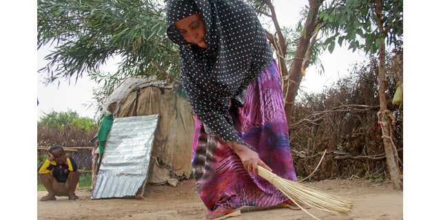 April 27, 2014: Ubah Mohammed Abdule, 33, center, sweeps the floor outside her hut as her son Abdullahi Yusuf Ahmed, 8, left, looks on in the Shedder refugee camp near the town of Jigjiga, in far eastern Ethiopia. (AP Photo/Elias Asmare)