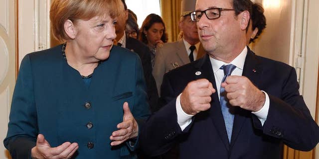 German Chancellor Angela Merkel, left, and French President Francois Hollande talk after a meeting on the sidelines of the ASEM summit of European and Asian leaders in Milan, northern Italy, Friday, Oct. 17, 2014. Russian President Vladimir Putin is looking to get relief from Western economic sanctions imposed since Russia's annexation of the Crimean Peninsula and its support for a pro-Russia insurgency in eastern Ukraine. To that end, he has scheduled a series of meetings on the sidelines of a two-day ASEM summit of European and Asian leaders. (AP Photo/Daniel Dal Zennaro, POOL)