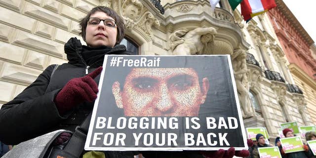FILE - In this Friday, Feb. 6, 2015 file photo, members of the Austrian Greens attend a protest against the detainment of Saudi blogger Raif Badawi in front of the KAICIID in Vienna, Austria. A Saudi blogger sentenced to 10 years in prison and 1,000 lashes for insulting Muslim clerics has won the European Union’s prestigious Sakharov Prize for human rights. Raif Badawi was honored with the award as a symbol of the fight for freedom of speech - an announcement greeted with a standing ovation Thursday, Oct, 29, 2015 at the European Parliament assembly in Strasbourg, France. “I urge the king of Saudi Arabia to free him, so he can accept the prize,” Parliament President Martin Schulz said. (AP Photo/Hans Punz, file)