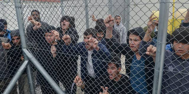 In this Saturday, Feb. 14, 2015, file photo migrants shout behind an iron fence at the Foreigners Detention Center in Amygdaleza, Greece, north of the capital Athens, following the apparent suicide of a Pakistani detainee. European Union countries are immersed in a full-fledged migration crisis. With the EU lacking funds and resources, some officials are even floating the idea of a multinational border guard to deal with arrivals of hundreds of thousands from war-torn countries like Syria, poor African nations and non EU neighbors like Kosovo. (AP Photo/ InTime News/Nikos Halkiopoulos, File) GREECE OUT