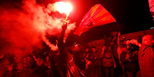 Feb. 2, 2012: An Egyptian waves a flare as others chant slogans during a protest in Tahrir Square in Cairo, Egypt.