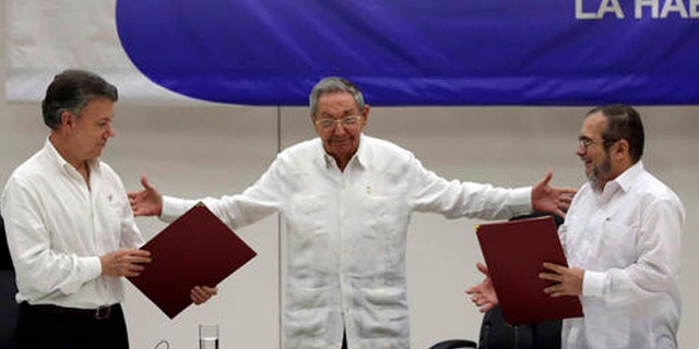 FILE - In this June 23, 2016 file photo, Cuba's President Raul Castro, center, motions to bring together Colombian President Juan Manuel Santos, left, and Commander of the Revolutionary Armed Forces of Colombia or FARC, Rodrigo Londono, better known as Timochenko or Timoleon Jimenez, during a signing ceremony of a cease-fire and rebel disarmament deal, in Havana, Cuba. Santos announced Friday, Sept. 2, 2016, that he will sign a peace accord with the FARC on Sept. 26. in Cartagena. (AP Photo/Ramon Espinosa, File)