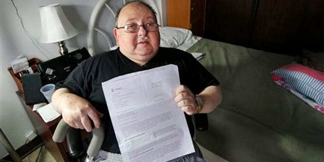 Belle Harbor Manor resident Robert Rosenberg, 61, who suffers from a spinal disability and has other chronic health problems, sits in his room in an assisted living facility in New York, Thursday, Nov. 6, 2014, where he and elderly, poor and disabled residents endured four months of misery after Superstorm Sandy flooded the center, located on New York's vulnerable Rockaway peninsula. Rosenberg holds a letter from the Federal Emergency Management Agency (FEMA) asking him to pay back all the federal disaster aid he received after the storm. He is among a dozen residents of Belle Harbor Manor who have been asked to return aid money. (AP Photo/Kathy Willens)