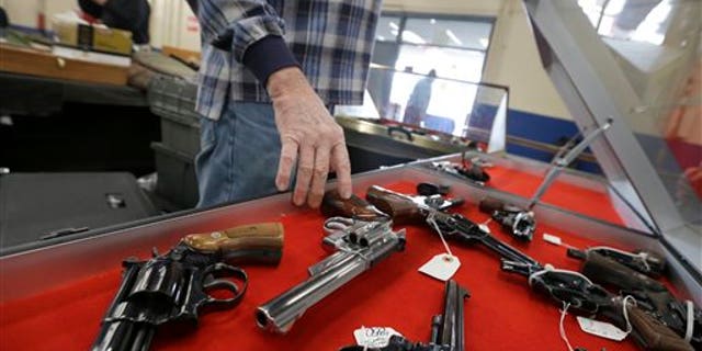 In this Friday, Feb. 6, 2015 photo, a dealer arranges handguns in a display case in advance of a show at the Arkansas State Fairgrounds in Little Rock, Ark. Arkansas gun advocates in the Legislature are supporting bills that would permit firearms on university campuses, expanding citizens' rights to use deadly force and other efforts. (AP Photo/Danny Johnston)