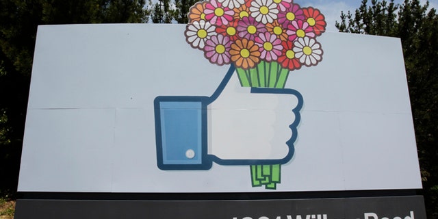 FILE - In this Sunday, May 13, 2012, file photo, flowers are added to a Facebook sign in front of Facebook headquarters in Menlo Park, Calif. On Tuesday, Feb. 4, 2014, Facebook celebrates 10 years since its inception. (AP Photo/Paul Sakuma, File)