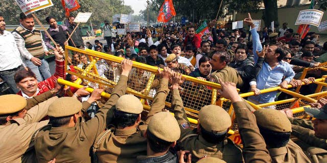 FILE - In this Feb. 4, 2011 file photo, activists of India's main opposition Bharatiya Janata Party (BJP) youth wing break police barricades at a protest in New Delhi, India, against alleged radio collars placed on Indian students of the Tri-Valley University in California. Several Indian students of the U.S. university, shut down on charges of a massive immigration fraud, were forced to wear radio collars around their ankles so that the U.S. authorities could keep a tab on their movements. Investigators say Tri-Valley was among the largest school fraud scams they encountered, involving hundreds of mostly Indian nationals living in cities as far away from Pleasanton as Miami, Chicago and Honolulu. (AP Photo/Mustafa Quraishi, File)