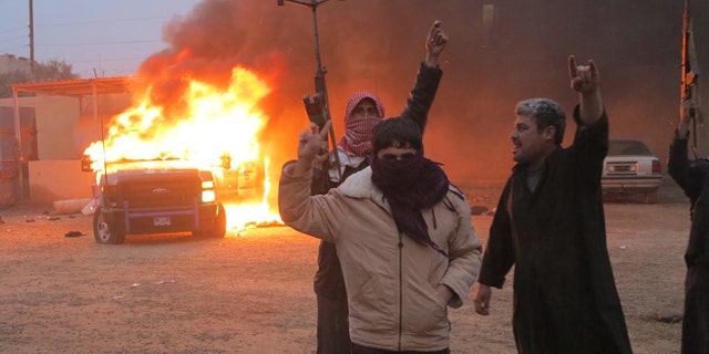 FILE: December 31, 2013: Protesters burn a police vehicle during fighting in Ramadi, in Iraq.
