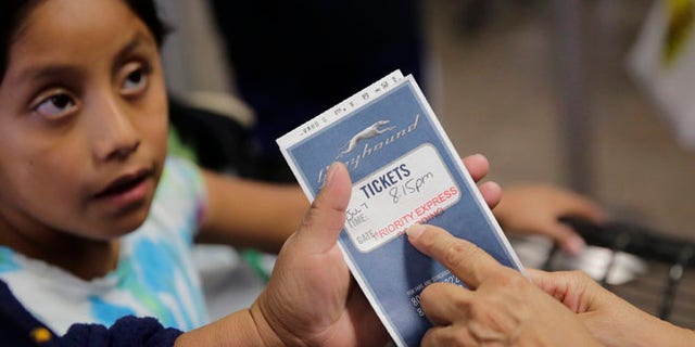 In this Tuesday, July 7, 2015, photo a volunteer helps immigrants from El Salvador and Guatemala who entered the country illegally prepare for a bus ride after they were released from a family detention center in San Antonio. Mothers with children are being released from Texas immigrant detention centers more quickly in the weeks since the nation's top immigration official announced policy changes, with far more being given ankle-monitoring bracelets in lieu of paying bonds, according to immigration attorneys. (AP Photo/Eric Gay)