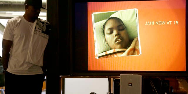 A recent photo of Jahi McMath on a video screen next to her uncle Timothy Whisenton in San Francisco, Wednesday, Dec. 23, 2015.