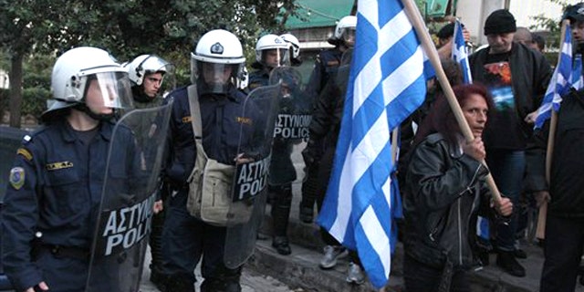 In this image taken Tuesday, Nov. 16, 2010 riot police look on a residents protest against Muslim immigrants holding outdoor prayers nearby.