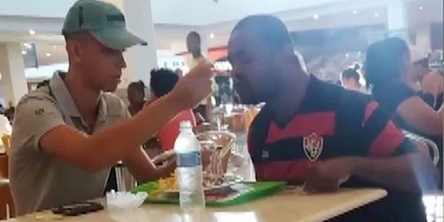 A Brazilian fast food employee has earned high praise online for taking time out of his day to feed a customer with an arm disability.