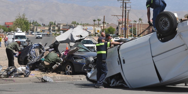 Authorities work on the scene of a fatal traffic accident in Hesperia, Calif, Sunday, May 11, 2014. A spokeswoman with the San Bernardino County Sheriff's Department says that four people are confirmed dead after a van smashed into a car that was sitting at a stop sign. (AP Photo/The Victor Valley Daily Press, David Pardo)