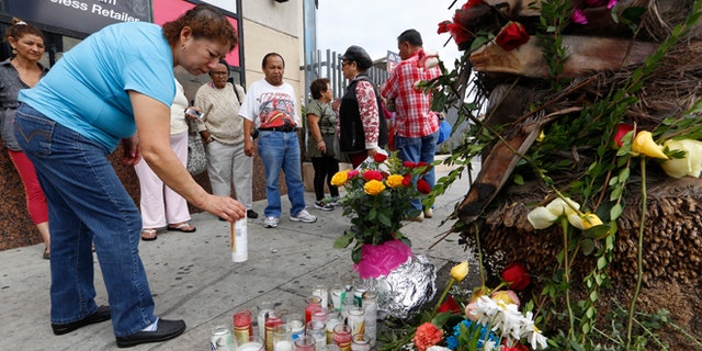 People gather at makeshift memorial at a tour bus stop in Los Angeles, Monday, Oct 24, 2016.