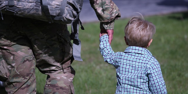 A father and son walk from a welcome-home ceremony for soldiers returning from Iraq on May 17, 2016 at Fort Drum, New York. (Photo by John Moore/Getty Images)