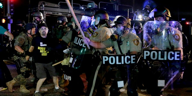 A man is detained after a standoff between protesters and police Monday, Aug. 18, 2014, during a protest for Michael Brown, who was killed by a police officer Aug. 9 in Ferguson, Mo. Brown's shooting has sparked more than a week of protests, riots and looting in the St. Louis suburb. (AP Photo/Charlie Riedel)