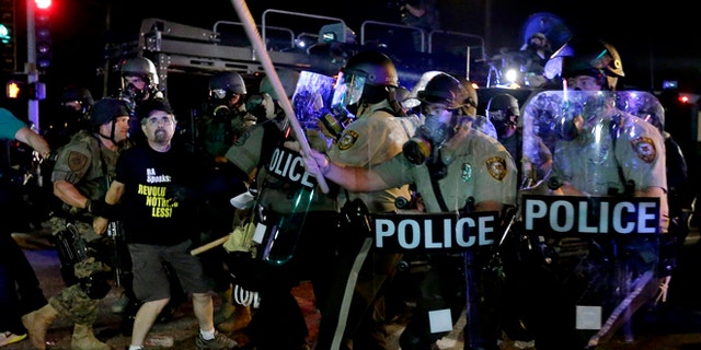 A man is detained after a standoff between protesters and police Monday, Aug. 18, 2014, during a protest for Michael Brown, who was killed by a police officer Aug. 9 in Ferguson, Mo. Brown's shooting has sparked more than a week of protests, riots and looting in the St. Louis suburb. (AP Photo/Charlie Riedel)