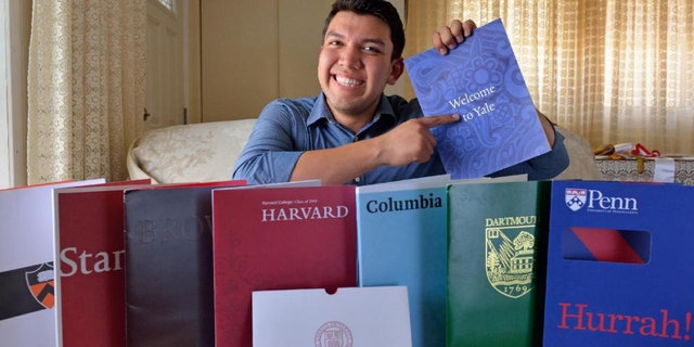 In this June 1, 2015 photo, Fernando Rojas, 17, a Fullerton High School graduate, poses for a photo in Fullerton, Calif. with literature from the eight Ivy League universities he was accepted into. He decided to attend Yale. (Leonard Ortiz/The Orange County Register via AP)