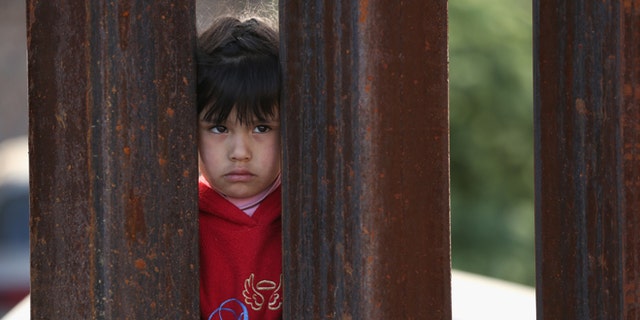 NOGALES, AZ - APRIL 01:  A child on the Mexican side of the U.S.-Mexico border fence looks into Arizona during a special 'Mass on the Border' on April 1, 2014 in Nogales, Arizona. Catholic bishops led by the Archbishop of Boston Cardinal Sean O'Malley held the mass at the border fence to pray for comprehensive immigration reform and for those who have died along the border.  (Photo by John Moore/Getty Images)