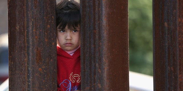 NOGALES, AZ - APRIL 01: A child on the Mexican side of the U.S.-Mexico border fence looks into Arizona during a special 'Mass on the Border' on April 1, 2014 in Nogales, Arizona. Catholic bishops led by the Archbishop of Boston Cardinal Sean O'Malley held the mass at the border fence to pray for comprehensive immigration reform and for those who have died along the border. (Photo by John Moore/Getty Images)