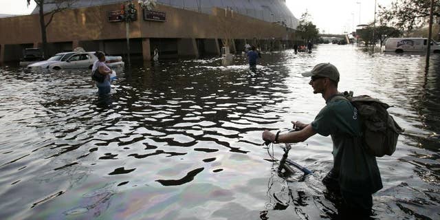 FILE - This Aug, 31, 2005 file photo shows a man pushing his bicycle through flood waters near the Superdome in  New Orleans after Hurricane Katrina left much of the city under water. A new but controversial study asks if an end is coming to the busy Atlantic hurricane seasons of recent decades. The Atlantic looks like it is entering in to a new quieter cycle of storm activity, like in the 1970s and 1980s, two prominent hurricane researchers wrote Monday in the journal Nature Geoscience.(AP Photo/Eric Gay, File)