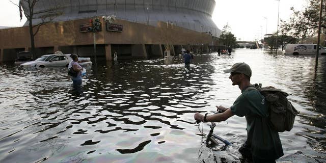 FILE - This Aug, 31, 2005 file photo shows a man pushing his bicycle through flood waters near the Superdome in New Orleans after Hurricane Katrina left much of the city under water. A new but controversial study asks if an end is coming to the busy Atlantic hurricane seasons of recent decades. The Atlantic looks like it is entering in to a new quieter cycle of storm activity, like in the 1970s and 1980s, two prominent hurricane researchers wrote Monday in the journal Nature Geoscience.(AP Photo/Eric Gay, File)