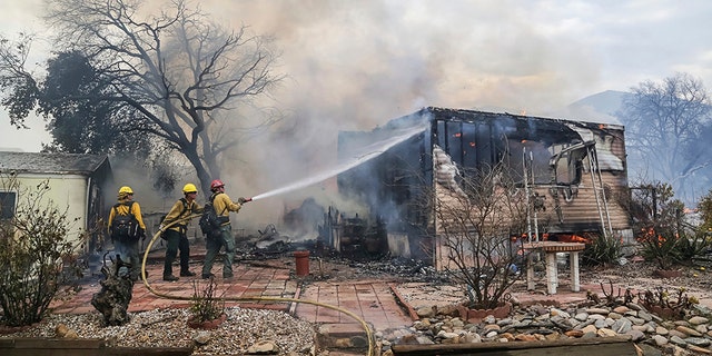 Firefighters battle flames at the Alpine Oaks Estates mobile home park during a wildfire Friday in Alpine, California.