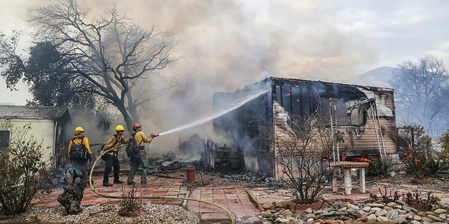 Firefighters battle flames at the Alpine Oaks Estates mobile home park during a wildfire Friday in Alpine, California.