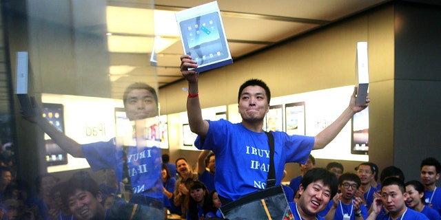 Han Ziwen holds up his iPads while being carried out by store employees at the Apple flagship store in Beijing, China, Friday, Sept. 17, 2010. Han was one of the first customers to officially buy an iPad in mainland China after lining up for more than 60 hours.