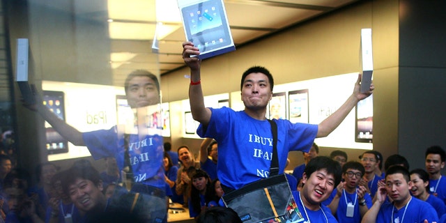 Han Ziwen holds up his iPads while being carried out by store employees at the Apple flagship store in Beijing, China, Friday, Sept. 17, 2010. Han was one of the first customers to officially buy an iPad in mainland China after lining up for more than 60 hours.