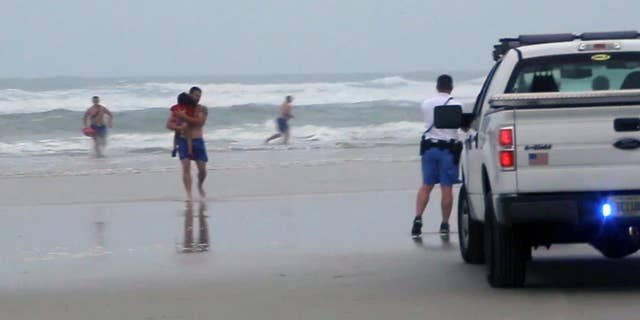 FILE - In this March 4, 2014 file image made from video, a lifeguard carries one of the three children rescued from a minivan that their mother, Ebony Wilkerson, drove into the Atlantic in Daytona Beach, Fla. Wilkerson as charged Friday with attempted first-degree murder and aggravated child abuse, though she has denied trying to harm anyone, authorities said. (AP Photo/Simon Besner, File) NO SALES