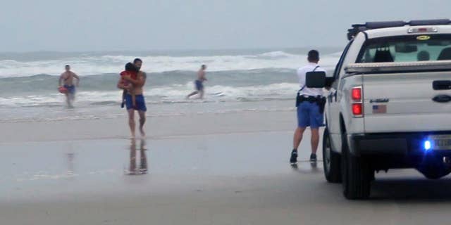 FILE - In this March 4, 2014 file image made from video, a lifeguard carries one of the three children rescued from a minivan that their mother, Ebony Wilkerson, drove into the Atlantic in Daytona Beach, Fla. Wilkerson as charged Friday with attempted first-degree murder and aggravated child abuse, though she has denied trying to harm anyone, authorities said. (AP Photo/Simon Besner, File) NO SALES