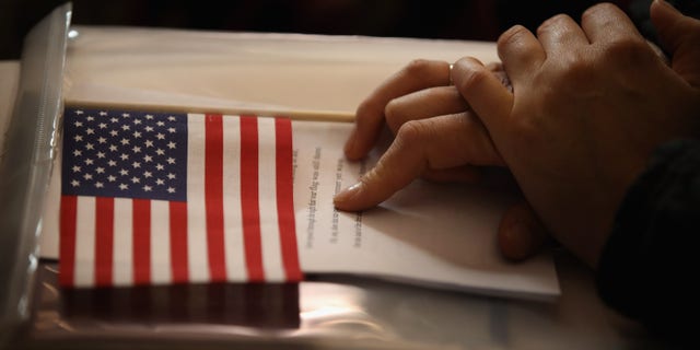 CHICAGO, IL - JULY 03: A new U.S. citizens holds and American flag along with her citizenship papers as she participates in a naturalization ceremony at the Chicago Cultural Center on July 3, 2013 in Chicago, Illinois. The ceremony, which recognized 71 new citizens from 32 countries, was one of more than 100 naturalization ceremonies held across the country and around the world to celebrate Independence Day. (Photo by Scott Olson/Getty Images)