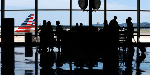 People ask questions at an information kiosk at Washington's Reagan National Airport after technical issues at a Federal Aviation Administration caused delays and cancellations on Saturday, Aug. 15, 2015.