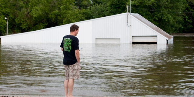 July 24: Sean Herdrich, of Manchester, Iowa, looks at his friend's downtown store for damage after the Maquoketa River flooded the area.