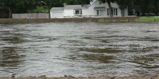 The Souris River passes near a home Tuesday, June 21, 2011, in Minot, N.D. About 11,000 Minot residents are being ordered to leave their homes even earlier than expected this week as the river gets closer to swamping the North Dakota city with the worst flooding in four decades, officials said Tuesday.