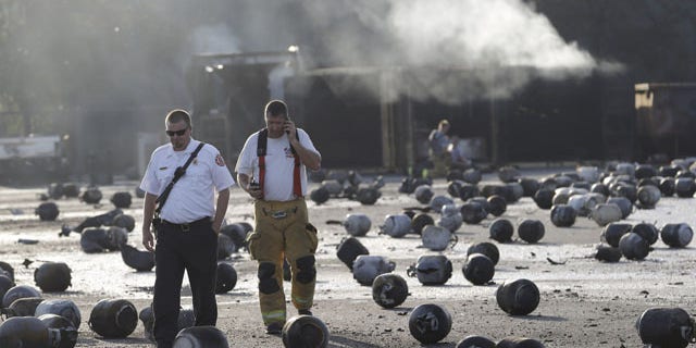 July 30, 2013: Firefighters walk through an area of exploded propane cylinders in the aftermath of an explosion and fire at a propane gas company in Tavares, Fla. (AP Photo)