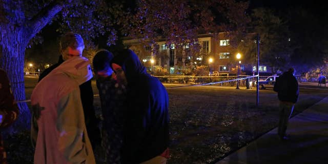 A group of students call their friends still locked down in Strozier Library, background, after a shooting on Thursday, Nov. 20, 2014, in Tallahassee, Fla. (AP Photo/Steve Cannon)