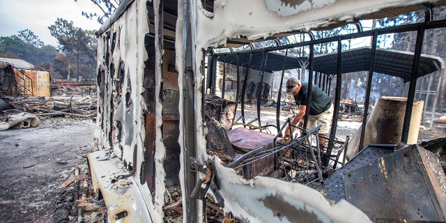 Mike Thornburg tries to salvage tools from a storage trailer on his mother's property on Ridge Road after wildfires ravaged the neighborhood in Eastpoint, Fla., Monday, June 25, 2018.