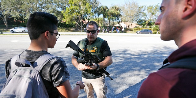A law enforcement officer talks with students after the shooting at Marjory Stoneman Douglas High School.