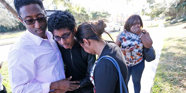 Family members hug a student after he exited Marjory Stoneman Douglas High School on Feb. 14, 2018, in Parkland, Fla.