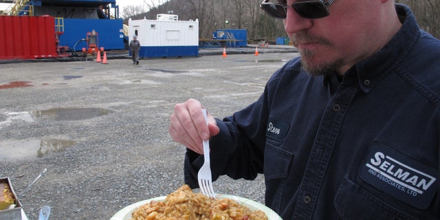 Geologist Steve Clark prepares to take a bite of jambalaya prepared for workers on a natural gas drilling site near Montoursville, Pa.