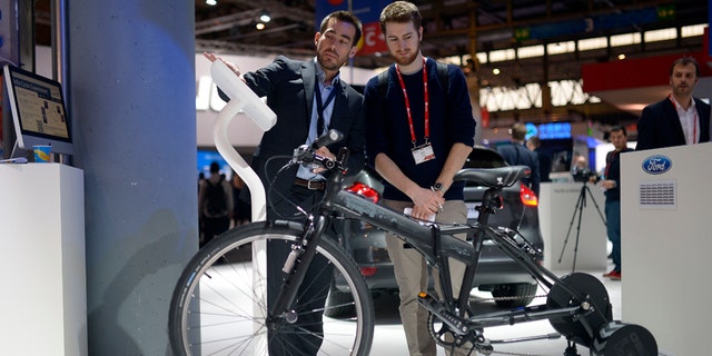 A worker shows a visitor the e-bike from Ford at the Mobile World Congress.
