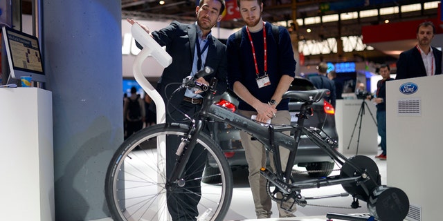 A worker shows a visitor the e-bike from Ford at the Mobile World Congress.