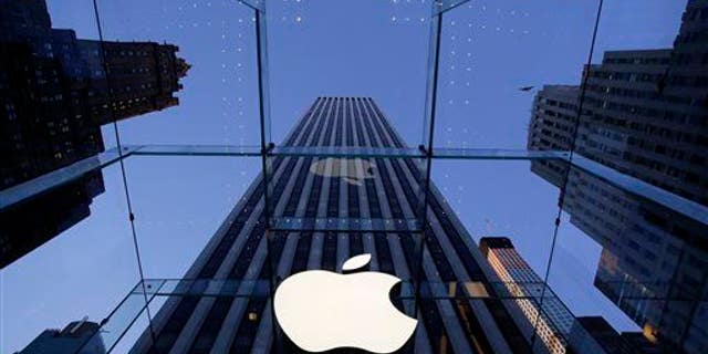 In this Sept. 5, 2014 file photo, the Apple logo hangs in the glass box entrance to the company's Fifth Avenue store, in New York.
