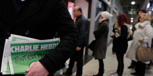 Jan. 14, 2015: A man leaves after buying Charlie Hebdo newspapers as people queue at a newsstand in Paris. (AP Photo/Christophe Ena)