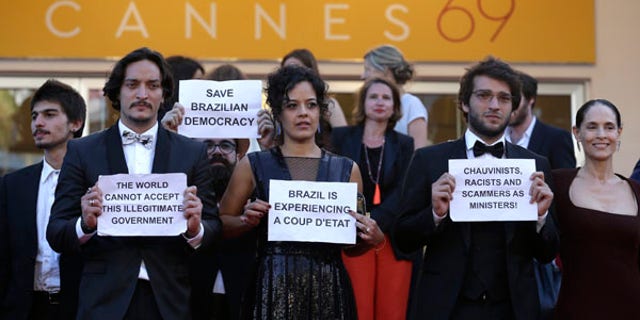 Cast from the Brazilian film Aquarius hold placards protesting against the current political landscape in Brazil after departing the screening of the film at the 69th international film festival, Cannes, southern France, Tuesday, May 17, 2016. (AP Photo/Lionel Cironneau)