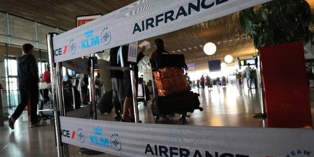Travellers walk past an Air France desk at Paris Charles de Gaulle airport, in Roissy, near Paris, Wednesday, Sept. 17, 2014. Air France canceled at least half its flights around the world on Monday as pilots began a weeklong strike, highlighting the trouble Europe's flagship airlines face in keeping up with low-cost competitors. (AP Photo/Christophe Ena)