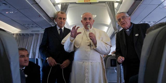 Pope Francis, flanked by Vatican spokesman father Federico Lombardi, first right, talks to journalists during a press conference he held aboard the papal flight on his way back from Strasbourg, eastern France, at the end of a one day visit to the European Parliament and Council, Tuesday, Nov. 25, 2014. Pope Francis has demanded Europe craft a unified and fair immigration policy, saying the thousands of refugees coming ashore need acceptance and assistance, not self-interested policies that risk lives and fuel social conflict. Francis made the comments Tuesday to the European Parliament during a brief visit meant to highlight his vision for Europe a quarter-century after St. John Paul II travelled to Strasbourg to address a continent still divided by the Iron Curtain. (AP Photo/Andrew Medichini)
